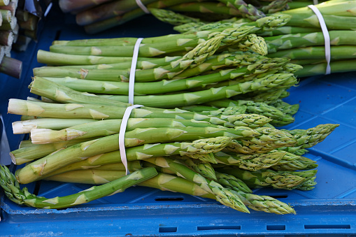 Bunch of fresh green asparagus shoots at retail market display, close up, high angle view
