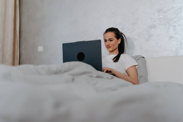 istock Woman Typing on Laptop in Bed 1477578424