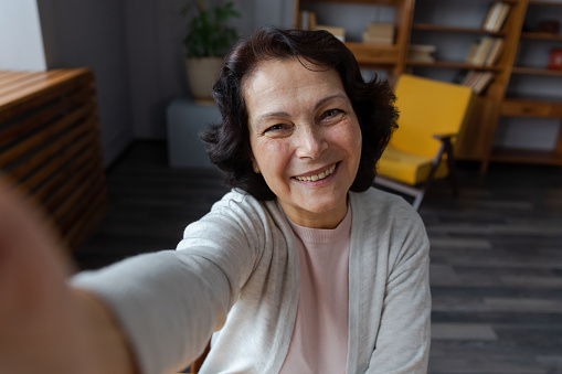 Happy middle aged senior woman talk on video call with friends family. Laughing mature old senior grandmother having fun speaking with grown up children online. Headshot portrait selfie webcamera view