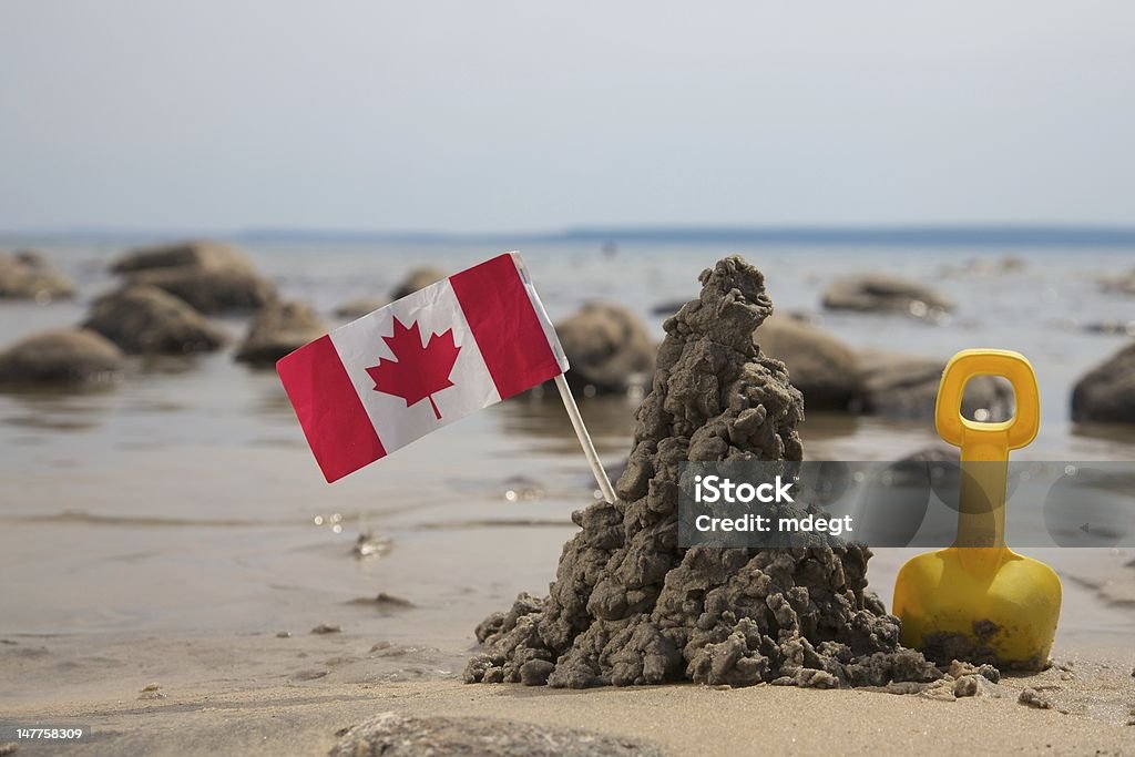 Spade, Mud Castle and Flag of Canada A Toy Spade, Mud Castle and Flag of Canada on a Sea Shore Canadian Flag Stock Photo