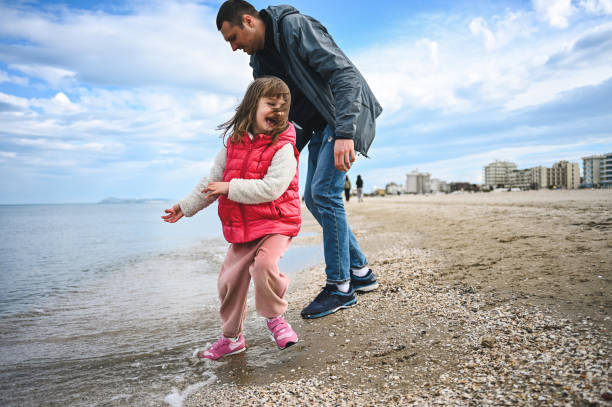 istock little girl laughing while playing with father outdoors on a sandy coastline. 1477584545