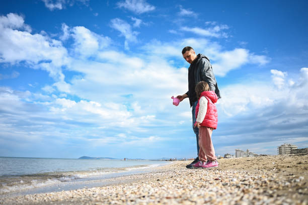 istock low angle view of a father with daughter on a coastline. 1477585191