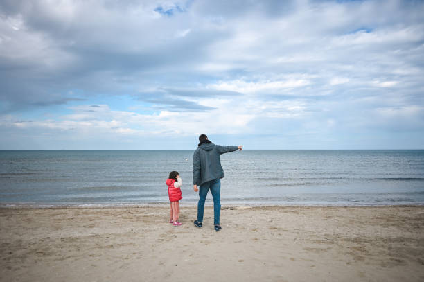 dad with a child enjoying the seascape in a cold spring day.