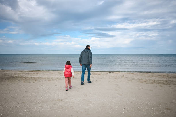 istock rear view of a family walking on a sandy empty beach. 1477585416
