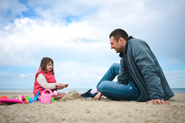 istock child with father relaxing on a winter beach. 1477585523