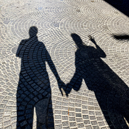 High angle view of couple shadow in the street on sidewalk.
