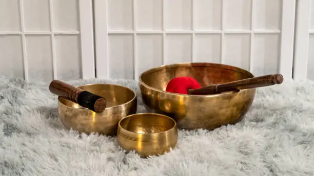 handmade Tibetan singing bowls with mallets on a fluffy rug, sound therapy for healing, relaxation and meditation