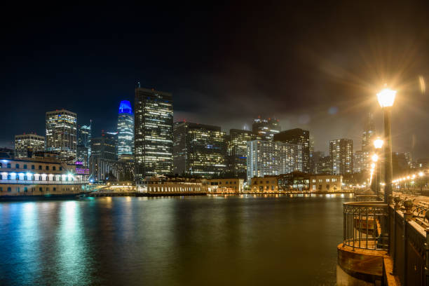 el horizonte del distrito financiero de san francisco está parcialmente envuelto en niebla por la noche - pier seven fotografías e imágenes de stock