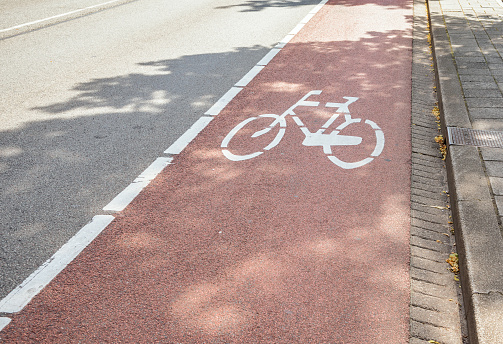 Bicycle lane marked in red along a street in a city centre on a sunny summer day. The Hague, Netherlands.