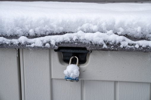 A lock on a storage shed unit, in the winter covered in snow