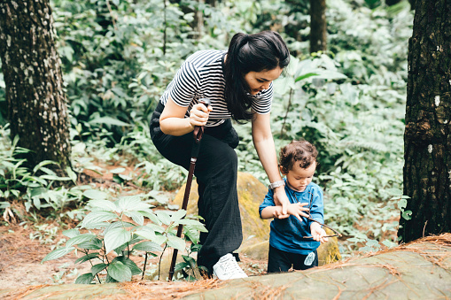 mother and curious toddler son hiking in woods