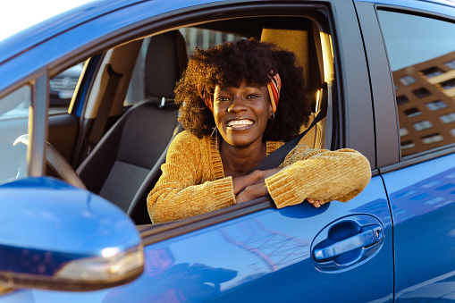 Smiling African-American woman sitting in the driver's seat and smiling while looking at the camera