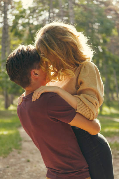 istock Handsome young man is holding up his girlfriend in a forest in the sunlight. 1477610507