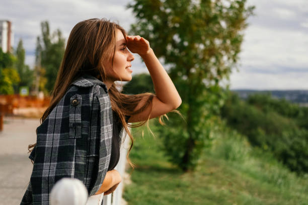 istock Romantic young woman is looking far while making shadow with a hand above eyes. 1477611054