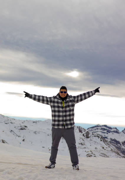 Profile shot of a man with skiing boots walking and carrying skis on a mountain