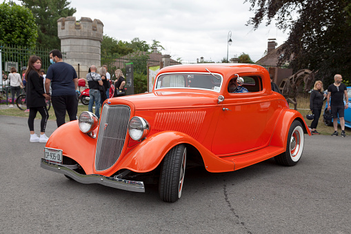 Buenos Aires, Argentina - Feb 25, 2024: Old white and orange 1934 Ford V8 model 40 coupe 5 window customized street rod at a classic car show in a parking lot. Front view. Grille. Copy space