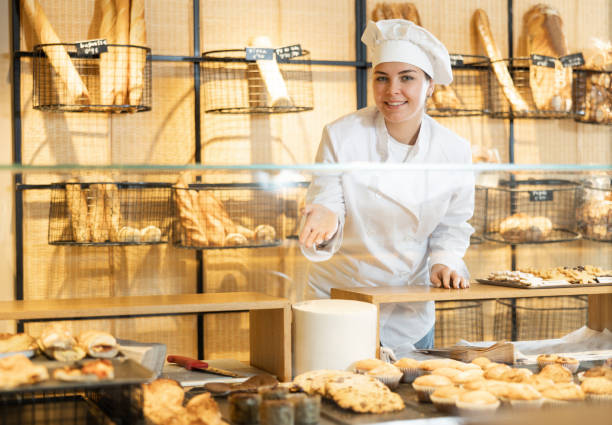 istock Young female baker presenting fresh baked products 1477622494