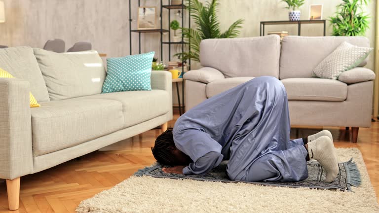 Young Muslim man praying at home