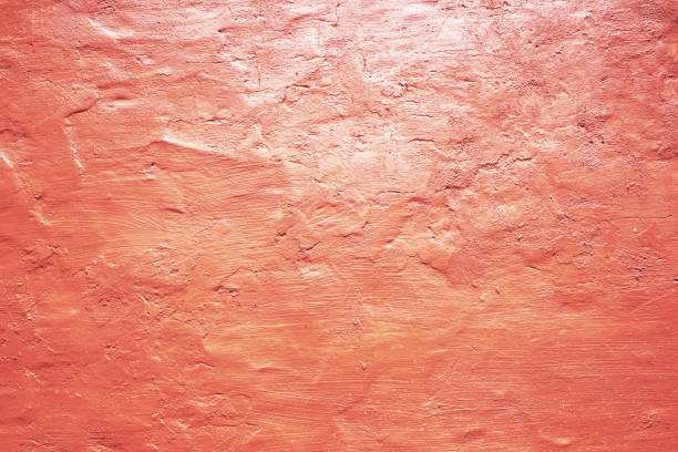 Light pale red coral abstract background. Peach pink color. Painted concrete wall with rough uneven plaster. Close-up.