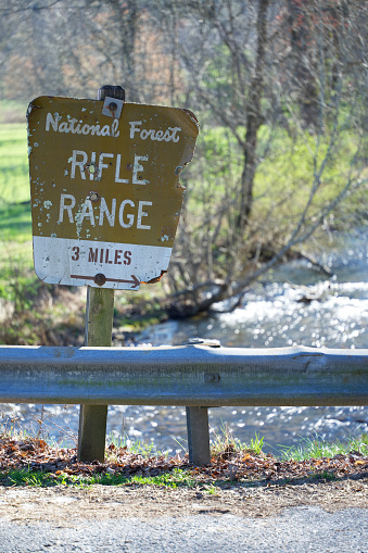 Close up of road sign for National Forest Rifle Range 3 miles