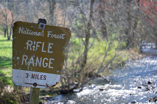 Close up of road sign for National Forest Rifle Range 3 miles