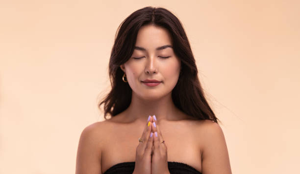 istock Asian woman meditating with clasped hands 1477641537