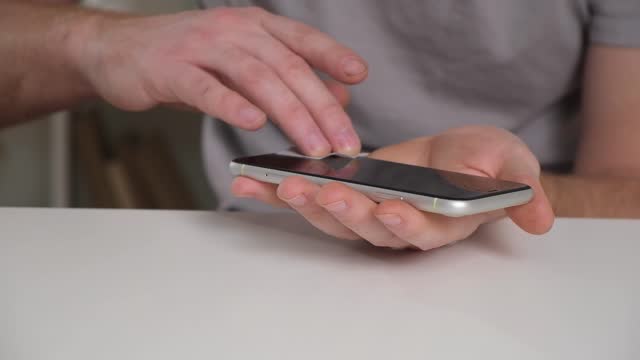 man cleans phone screen stick protective tempered glass. Broken glass iPhone XR. Georgia, March 2023