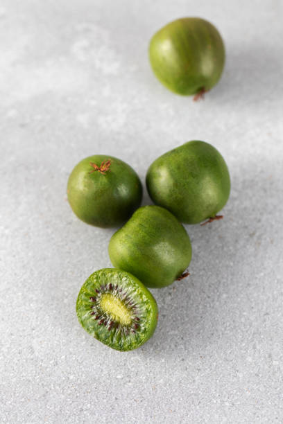 Mini kiwi on a gray table, whole and half. Tropical fruits. Kiwi berry. Mini kiwi on a gray table, whole and half. Tropical fruits. mini kiwi stock pictures, royalty-free photos & images