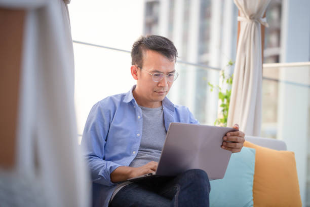 istock Asian man using laptop sitting on sofa at home, Man working from a laptop at the terrace 1477644465