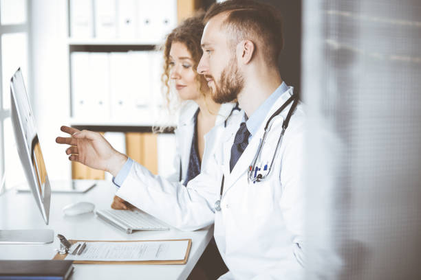 istock Red-bearded doctor with female colleague discussing current disease therapy while sitting at working place in clinic. Team work in medicine 1477650178