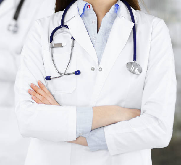 une jeune femme médecin inconnue se tient debout, les bras croisés, à la clinique. concept de médecine pendant la pandémie de coronavirus - portrait doctor paramedic professional occupation photos et images de collection