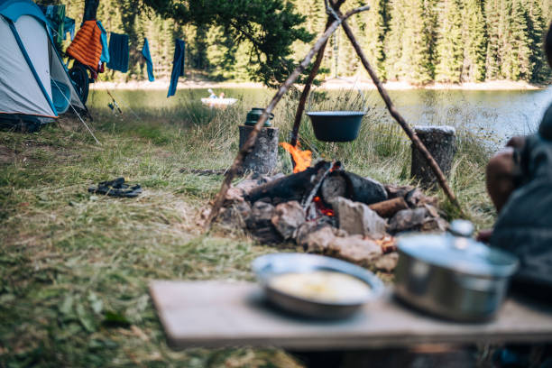 istock Man cooking a soup in a pot over the campfire. 1477652640