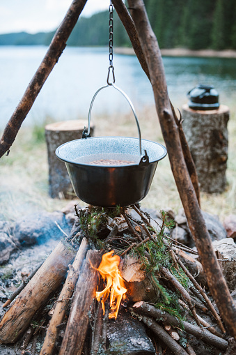 Hanging pan over the campfire with meal cooking in it.