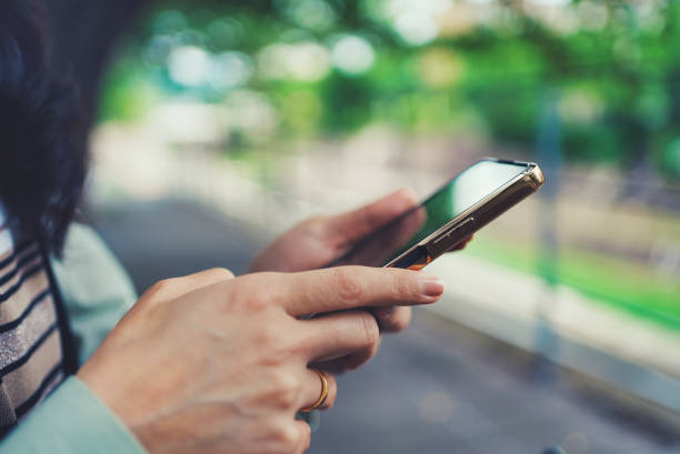 istock Woman looking at smartphone and green blur background 1477665876