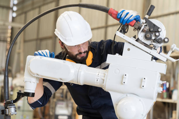 istock Male engineer worker working at work with automatic welding robotic arm machine in factory. Male technician worker checking, repair automatic welding robot arm machine at production line 1477672312