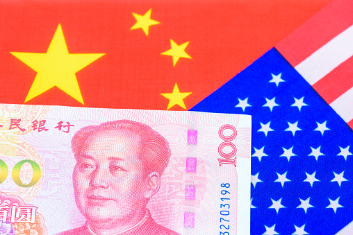 Trade tension, trade war or commercial conflict between US and China, economic concept : Chinese yuan or renminbi bill with the American flag. Depicting the trade war between the two major economies.