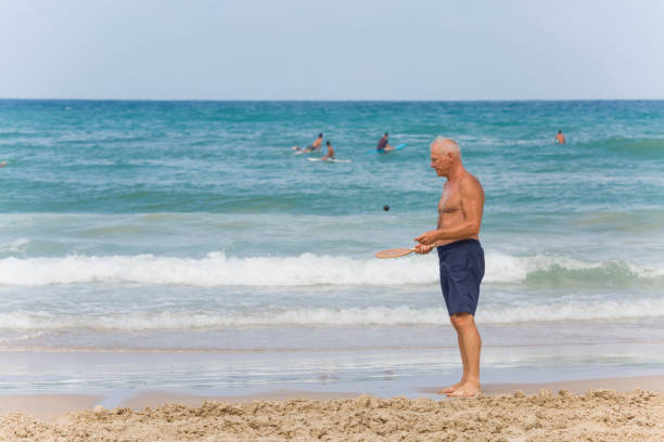 istock A mature man trains with a ball before playing matkot on the beach. 1477684836