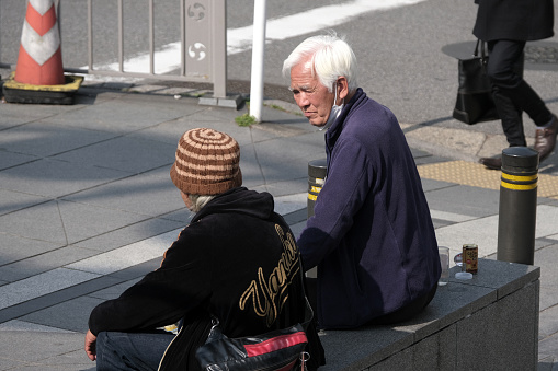 Two local senior men sitting and chatting along a street in Asakusa, a district in Taitō, Tokyo, Japan.