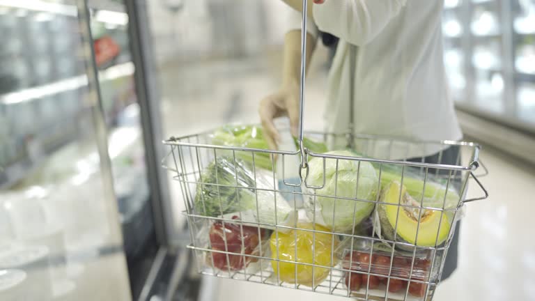 Close Up Of Woman With Shopping Basket Buying Food In Supermarket