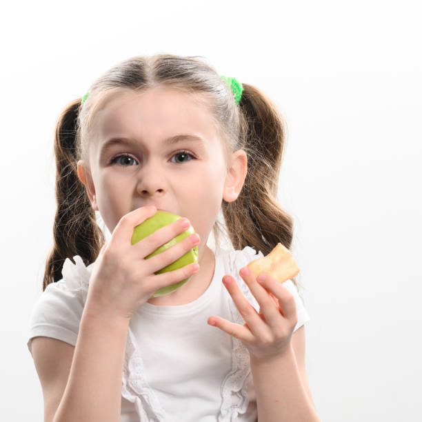 istock A little girl is holding one apple and chips on a white background. 1477693359