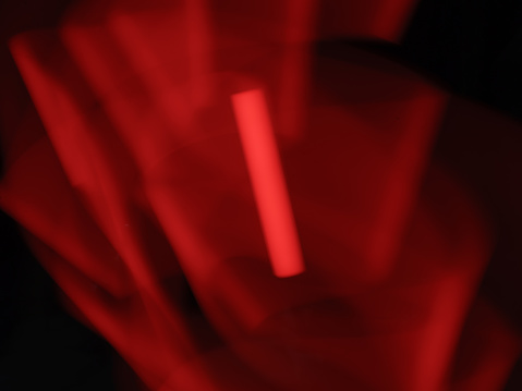 Waves of the bright red light at night. Black background. Motion of the red romantic light. Textured effect. Abstraction