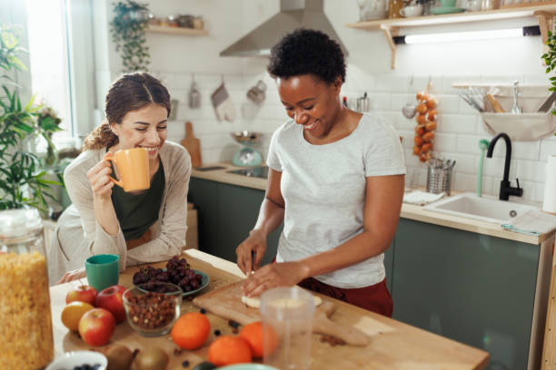 istock Female friends having fun in kitchen while cutting fruits for smoothie 1477702345