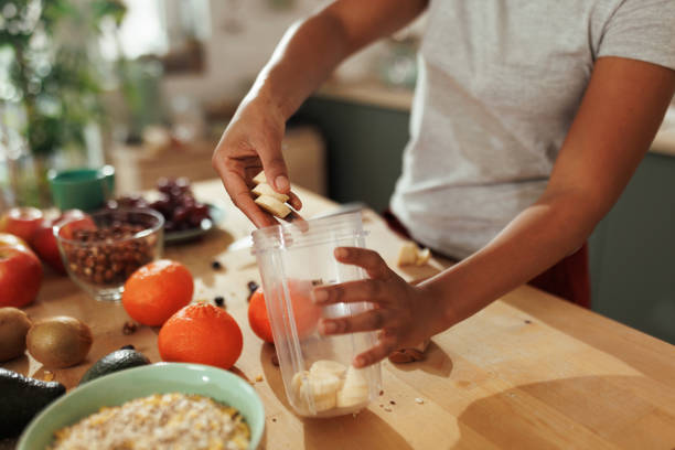 Mixed dried fruits spill from a transparent glass jar onto a brown fabric surface. The diverse assortment includes apples, apricots, and plums, creating a colorful, rustic display.