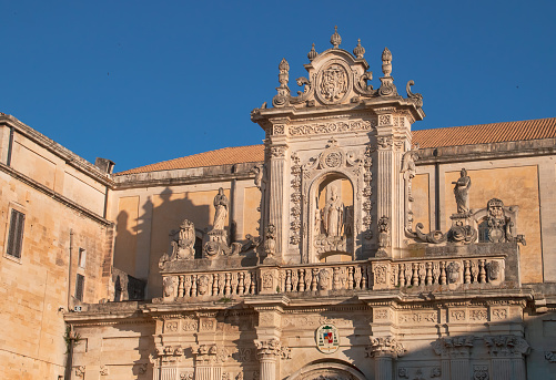 Baroque architectural details of the entablature above the portal with the statue of Saint Orontius in the center.