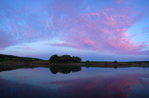 Bright purple sunset the river in the water reflects the clouds and trees a quiet autumn evening.