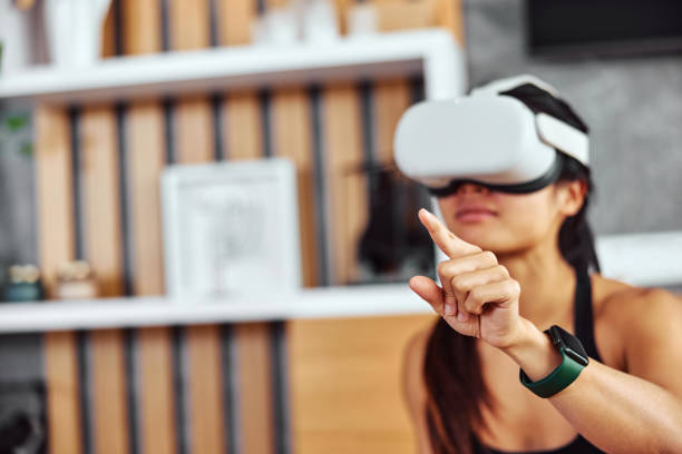 istock An Asian woman in a virtual world, using a VR headset, having fun at home. 1477705695