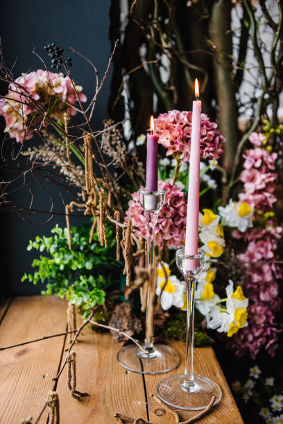 istock Decor with pink candles, yellow flowers narcissus, dry plant, tree bark. Easter zone with rustic design, spring branches, black wall. Arch autumn floral for photo sessions.  Birthday party detail. 1477707343