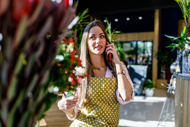 istock A young beautiful woman is talking using a phone in a flower shop. 1477707745