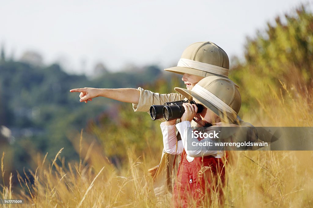 Exploring kids Happy young safari adventure children playing outdoors in the grass with binoculars and exploring together as brother and sister. Safari Stock Photo