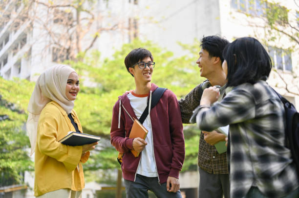 A group of happy young Asian-diverse college students are enjoying talking in the campus park stock photo